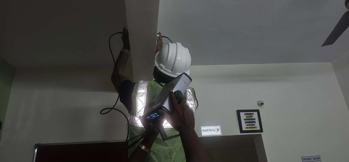 Engineer performing ultrasonic pulse velocity test on concrete wall